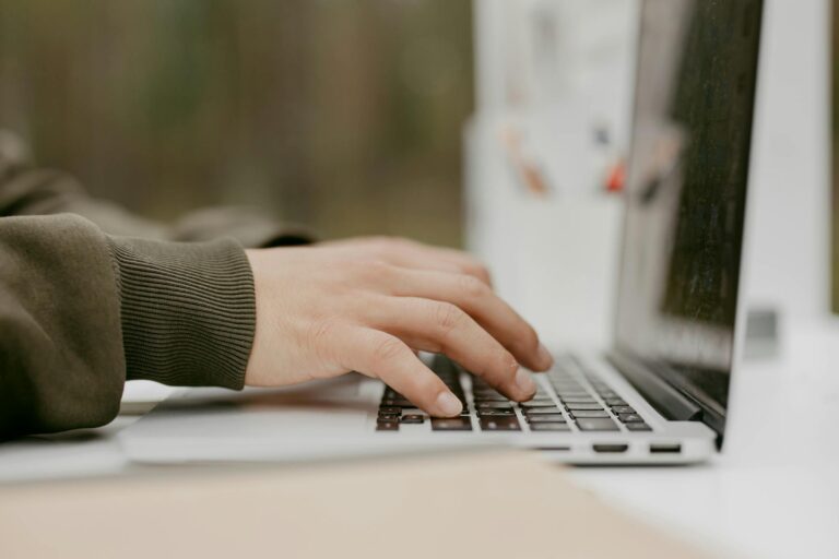 Close-up of hands typing on a laptop keyboard, ideal for technology and lifestyle themes.